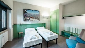 A room with two beds, a green wall, a painting, a green bench, and a blue chair. - Maison Ammiragli Vatican Rooms (Roma)