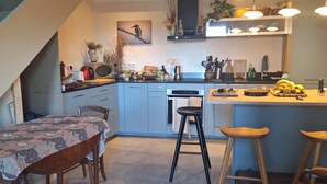 Een moderne keuken met een eethoek, voorzien van een trap, een magnetron, een spoelbak en diverse keukengerei.