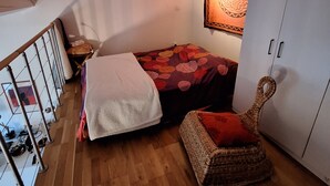 Een slaapkamer met een bed, een stoel, een kledingkast en een wandtapijt.