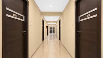 A hotel hallway with dark wooden doors, beige walls, and a tiled floor.