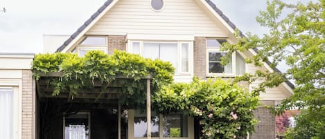 A house with a covered patio, a brick wall, and a window.
