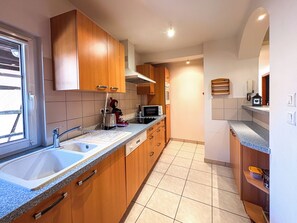 A modern kitchen with wooden cabinets, a double sink, a microwave, and a toaster. - Spacious vacation rental "Les Petits Bouchons" between Eguisheim and Colmar in the vineyards (Wettolsheim)