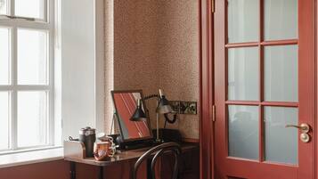 Una habitación con escritorio, silla y una puerta roja.