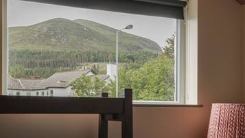 A room with a window overlooking a mountainous landscape.