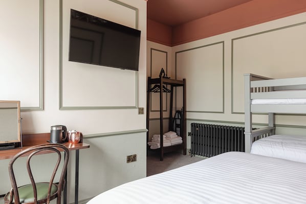 A hotel room with a bunk bed, a desk with a chair, a radiator, and a television mounted on the wall. - Avoca House (Newcastle)