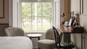 A hotel room with a bed, two chairs, a small table, and a desk with a lamp. - Avoca House (Newcastle)