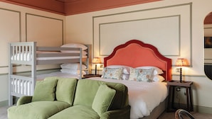 A hotel room with a bunk bed, a green armchair, two bedside tables with lamps, and a large framed artwork on the wall. - Avoca House (Newcastle)