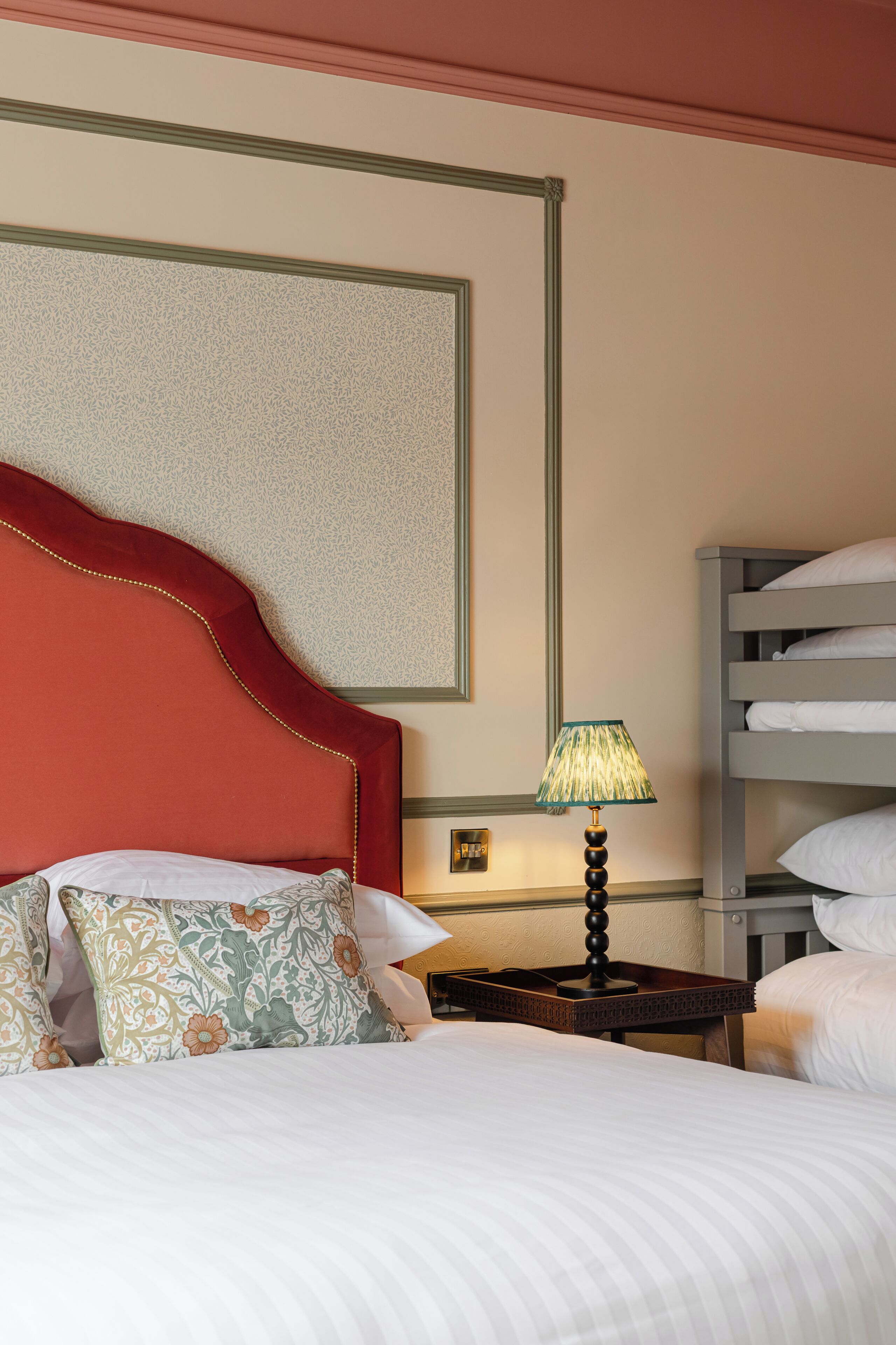 Ein Hotelzimmer mit einem Bett, einem Nachttisch, einer Lampe und einem Stockbett.