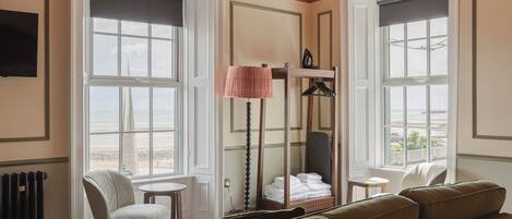 Habitación de hotel con un ventanal grande, una silla, una mesa, un sofá y un radiador.