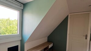 Une pièce avec un plafond en pente, une fenêtre, une porte et un banc.