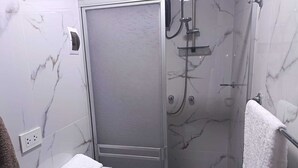 Un bagno con doccia, un portascopevoli e una porta.