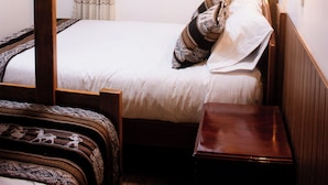 Una stanza piccola con un letto a castello, un letto singolo, un comodino e una finestra con tende.