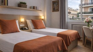 A hotel room with two beds, a desk, a chair, a window with a view of buildings, and a radiator. - Flat Near Las Ventas District (Madrid)
