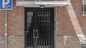 A building entrance with a black metal gate, a blue parking sign, and a wheelchair accessibility symbol. - Flat Near Las Ventas District (Madrid)