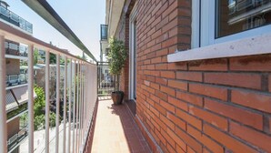 A narrow balcony with a brick wall, a window, and a potted plant. - Flat Near Las Ventas District (Madrid)