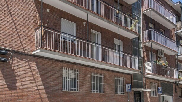 A multi-story brick building with balconies, a parking sign, and a bicycle. - Flat Near Las Ventas District (Madrid)