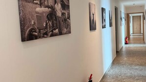 Un pasillo con obras de arte en las paredes, un extintor y una puerta al final.