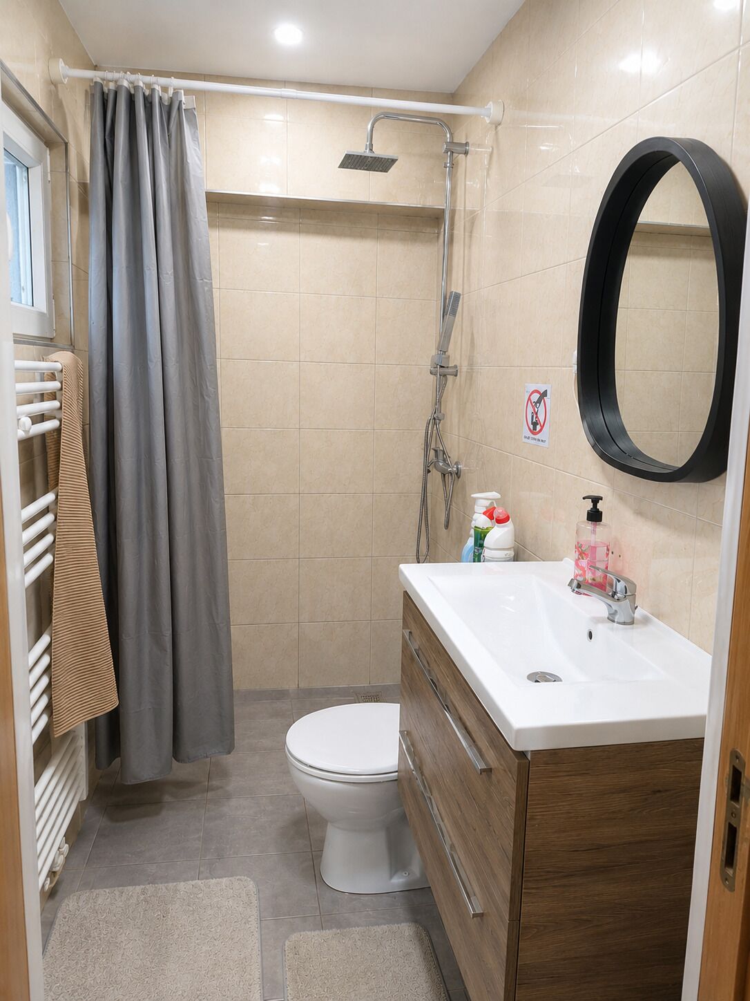 A bathroom with a shower, toilet, sink, and a towel rack.