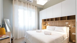 Ein modernes Hotelzimmer mit einem großen Bett, einem Schreibtisch mit Spiegel und einem fenster mit Vorhängen.