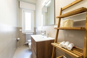 Une salle de bain avec un meuble-lavabo en bois, un lavabo blanc, un miroir et un porte-serviettes avec des serviettes.