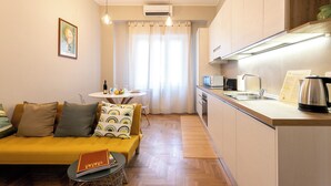 Ein gemütlicher Wohnbereich mit Sofa, kleinem Tisch, einer Küchenzeile und einem Essbereich.