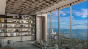 Un interno moderno con un'ampia vetrata, una libreria a muro e un'area salotto.