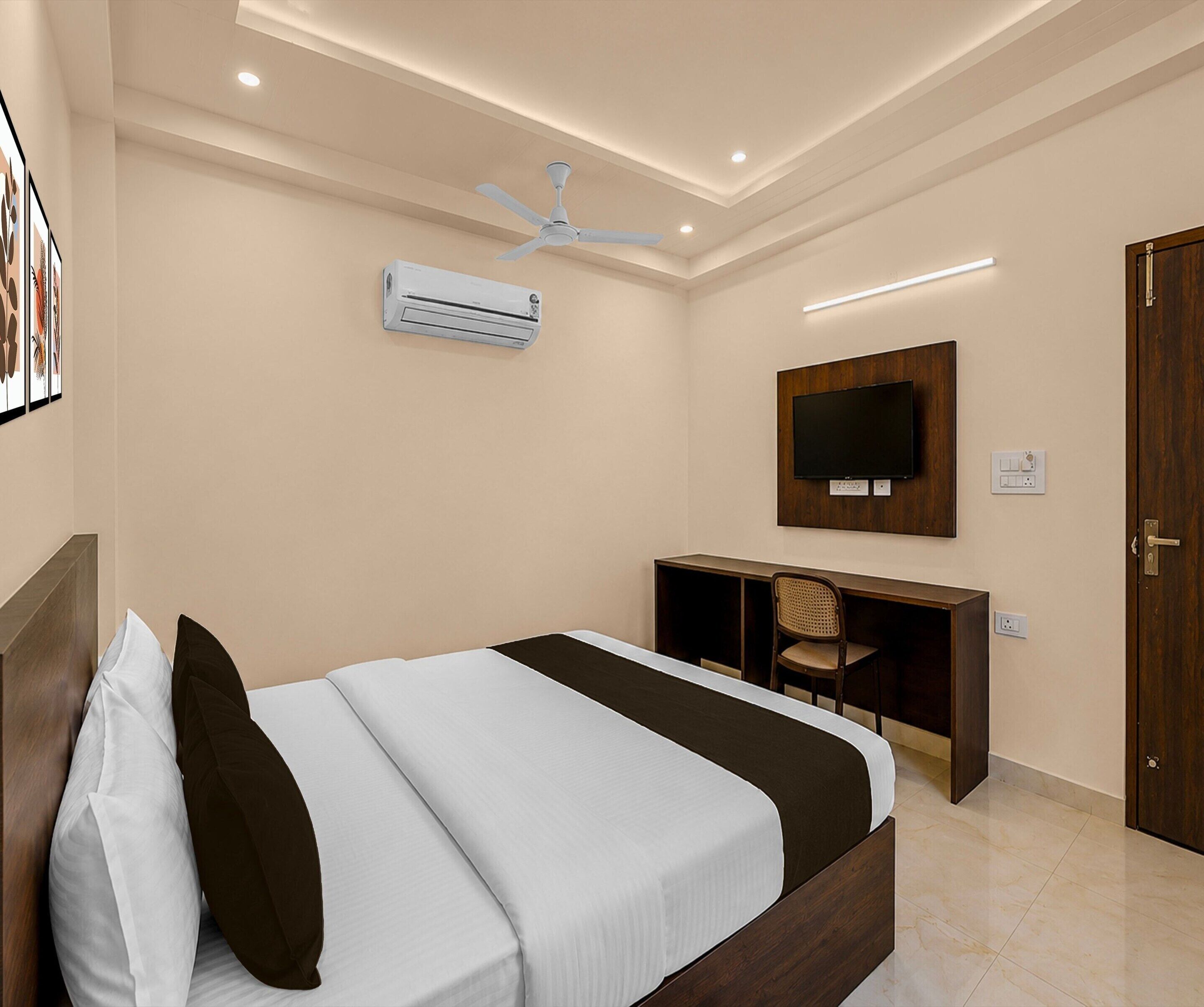 Une chambre d’hôtel équipée d’un lit, d’un bureau, d’une chaise, d’une télévision, d’un climatiseur et d’une porte.