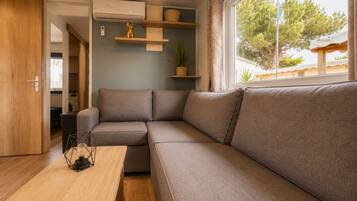 Ein zeitgemäßer Wohnbereich mit einer Couch, einem Holztisch und einem Fenster mit Blick auf Bäume.
