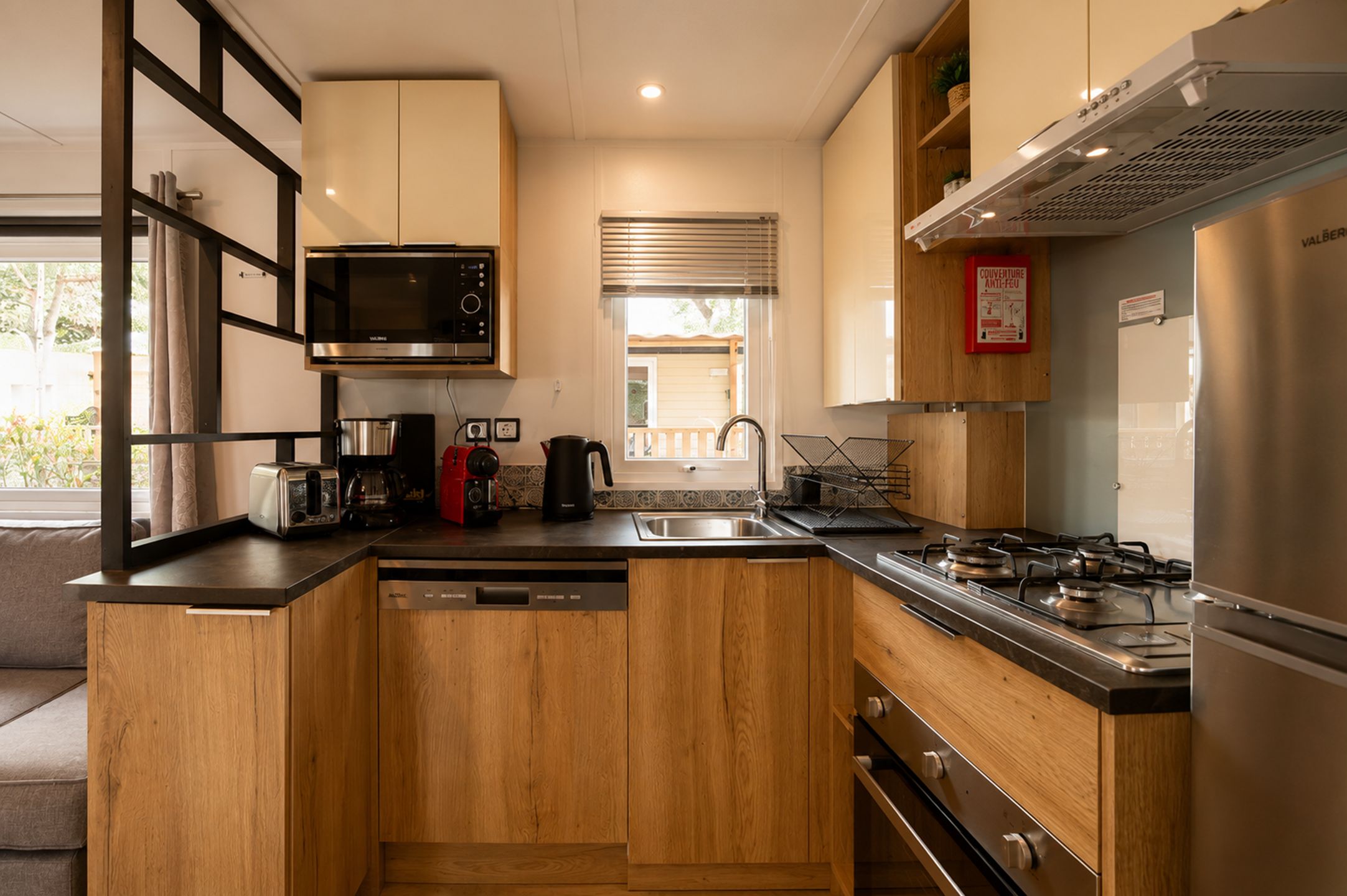 Una cocina moderna con armarios de madera, electrodomésticos de acero inoxidable y una ventana con persianas.