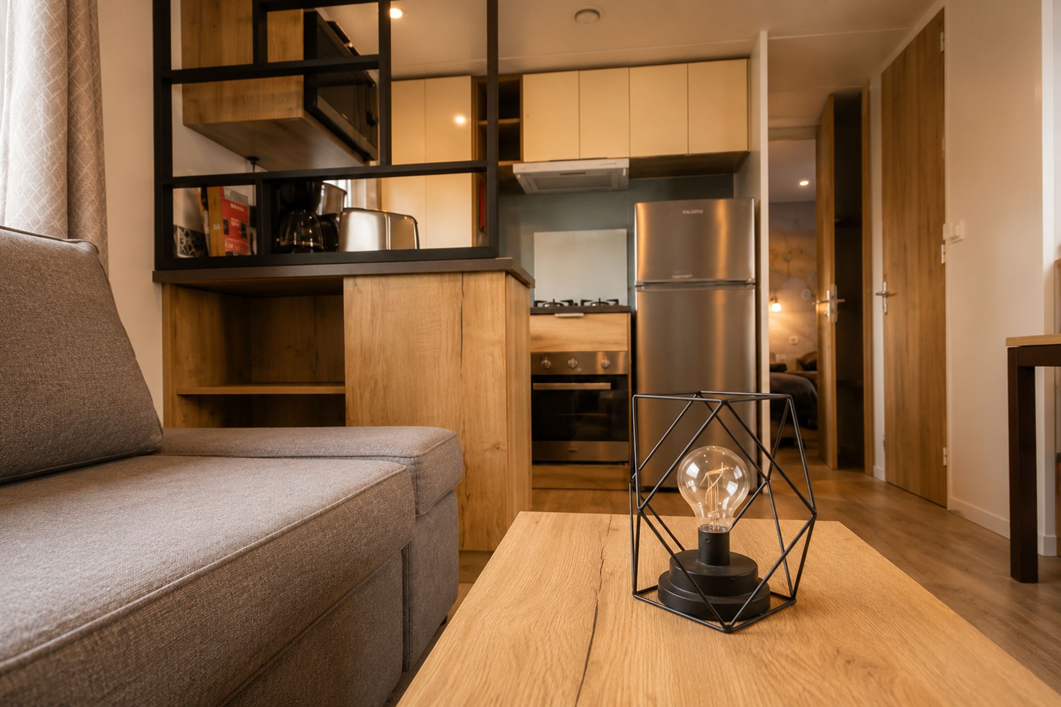 Ein modernes Wohnzimmer mit einer Couch, einem Couchtisch und einer Küche im Hintergrund.