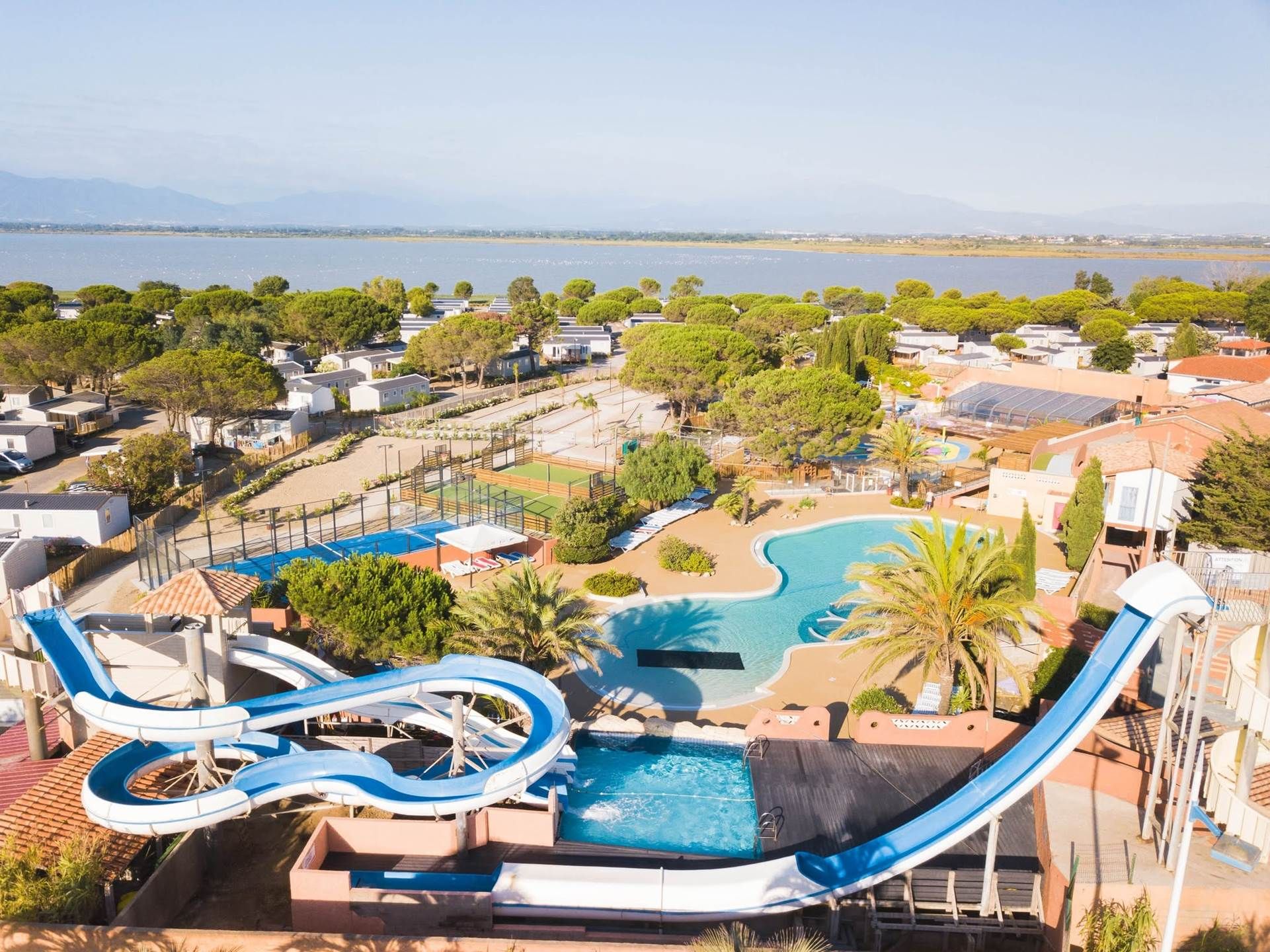 Parque acuático con varias toboganes y una piscina, rodeado de edificios residenciales y árboles.
