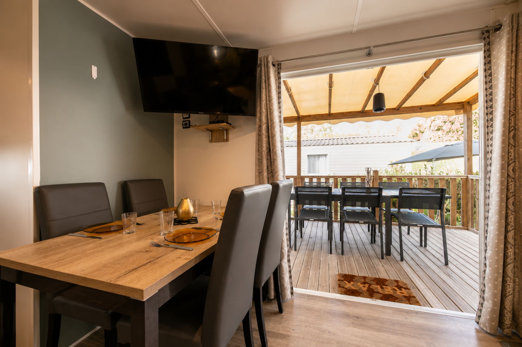 Ein Essbereich mit Holztisch, Stühlen und einem an der Wand befestigten Fernseher.