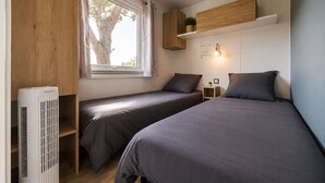 A bedroom with two beds, a window, a wall-mounted shelf, a bedside table, and a radiator. - Le Cocon du Mar Estang - Terrace, air conditioning, sleeps 8 (Canet-en-Roussillon)