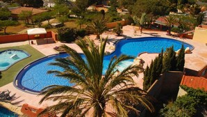 A residential area with a large swimming pool surrounded by palm trees and a view of a lake. - Le Cocon du Mar Estang - Terrace, air conditioning, sleeps 8 (Canet-en-Roussillon)
