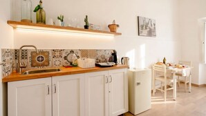 Una cocina con encimera de madera, armarios blancos, un fregadero y una zona de comedor con mesa y sillas.