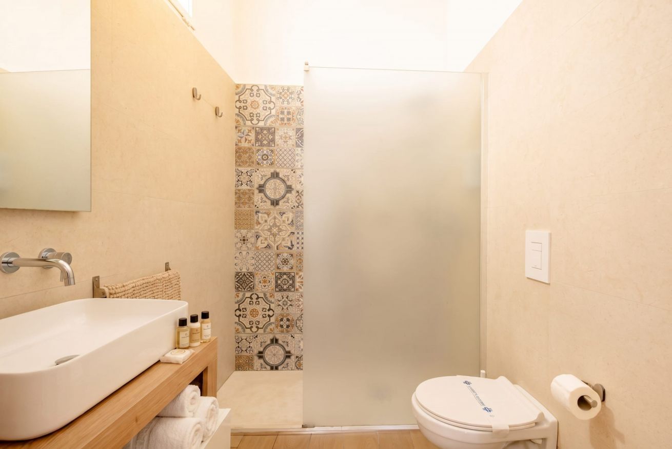 Un bagno con un lavandino capiente, un water e uno spazio doccia.