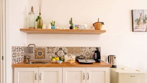 Cocina con encimera de madera, un lavamanos y una cafetera. Hay dos armarios debajo de la encimera.