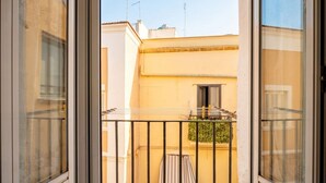 Un balcón con vista a un edificio, una ventana y una barandilla.