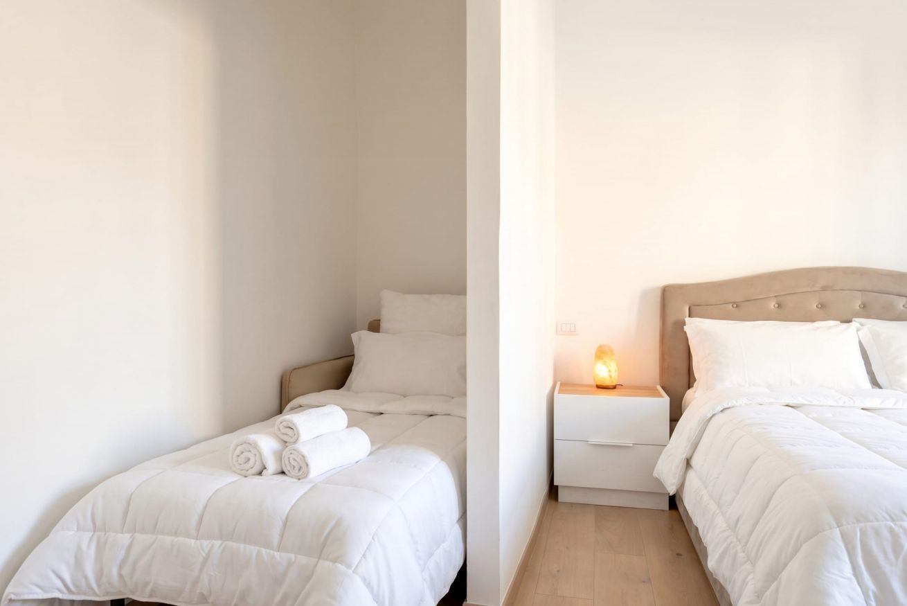 Une chambre d’hôtel avec un lit, une table de chevet et une lampe fixée au mur.