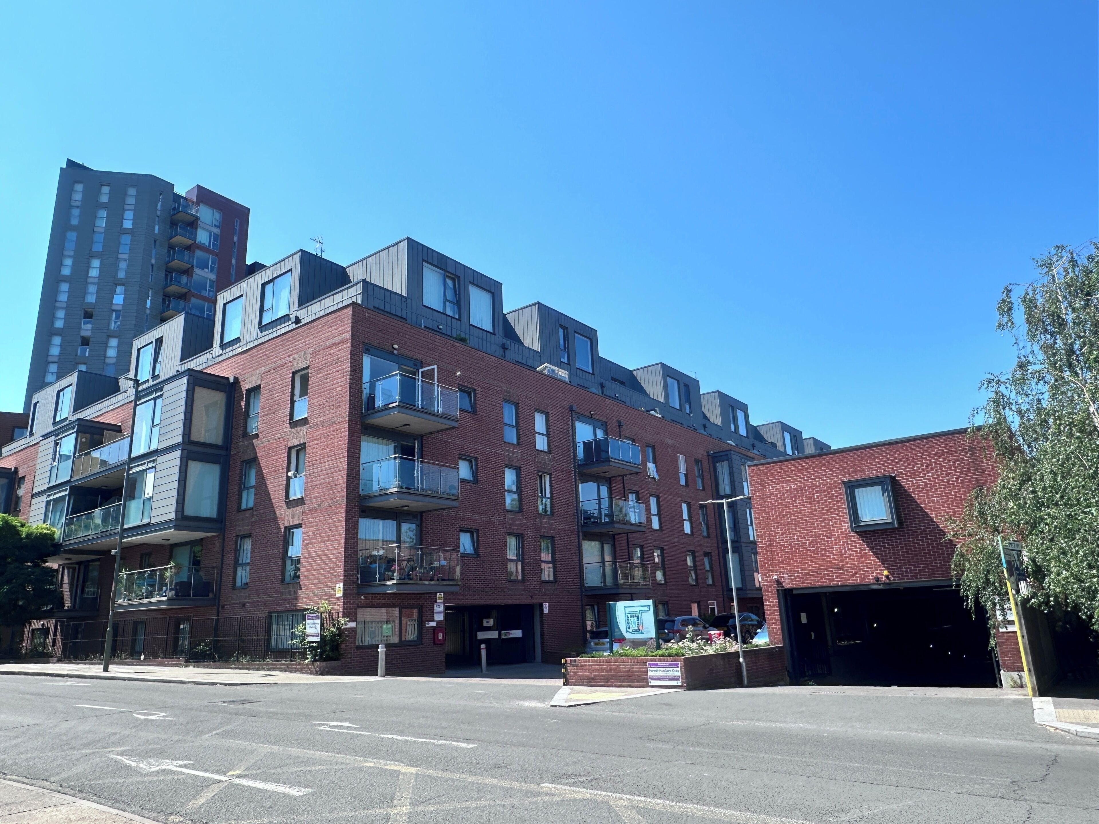 A multi-story building with balconies, a garage, and a clear sky.