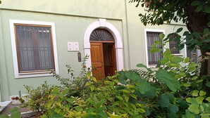 Ein Gebäude mit grüner Fassade, einer Holztür und einem Fenster mit Metallgitter.