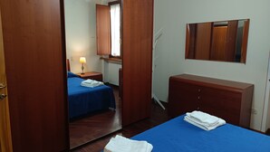 Ein Hotelzimmer mit zwei Betten, einem Holzschrank, einem Spiegel und einer Heizung.