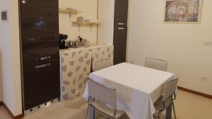 Ein kleines Zimmer mit einer Küchenzeile, einem Esstisch und einem Stuhl.