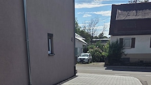 En asfalterad gångväg leder fram till en byggnad med ett fönster och siffran ’46’ på väggen.