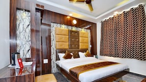 Ein Hotelzimmer mit einer Marmorwand, einem Bett mit Holz Kopfteil, einem Schreibtisch, einem Stuhl und einem gemusterten Vorhang.