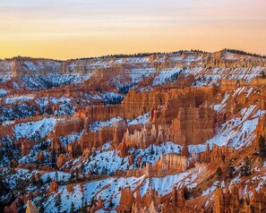 Ein weitreichender Blick auf eine zerklüftete Canyonlandschaft mit schneebedeckten Gipfeln und wolkenlosem Himmel.