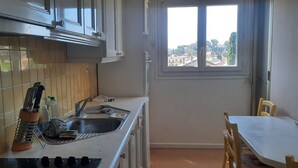 Uma cozinha com pia, janela com vista e mesa de jantar com cadeiras.