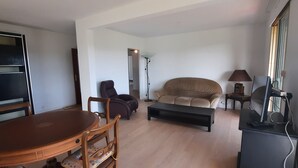 Uma sala de estar com uma mesa de jantar de madeira, um sofá, uma mesa de centro e um rack para TV.