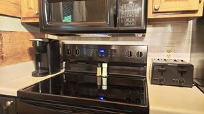 A kitchen with a black stove, a microwave, and a toaster. - Mountain getaway 6 mins to attractions + 2 king beds + hot tub + fire pit (Sevierville)
