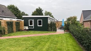 A residential property with a well-maintained lawn, a small shed, and a patio area with a blue umbrella. - Beautiful Accommodation in De Kiel (De Kiel)